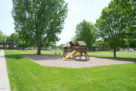 A playground with a yellow slide and a brown wooden structure.