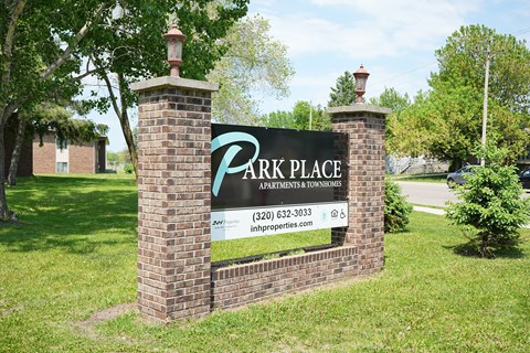 A sign for Park Place Apartments and Townhomes is displayed in front of a grassy area.