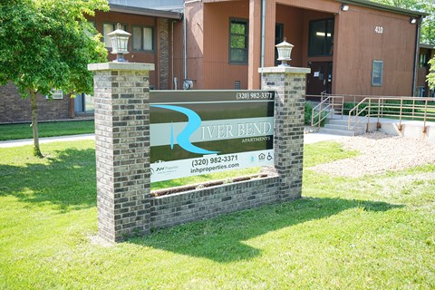 A sign for River Bend Apartments stands in front of a building.