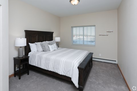 A bedroom with a large bed and two lamps.