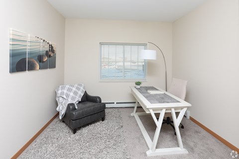 A room with a table, chair, and a painting on the wall.