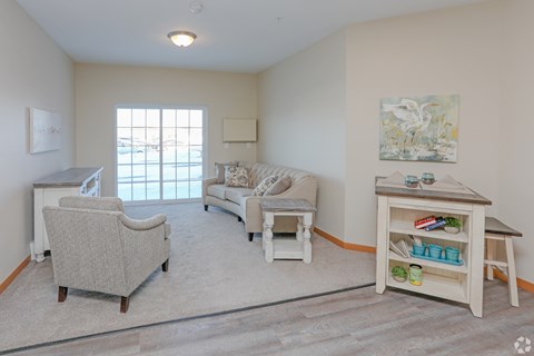 A living room with a grey sofa, a white chair and a wooden table with a painting on the wall.