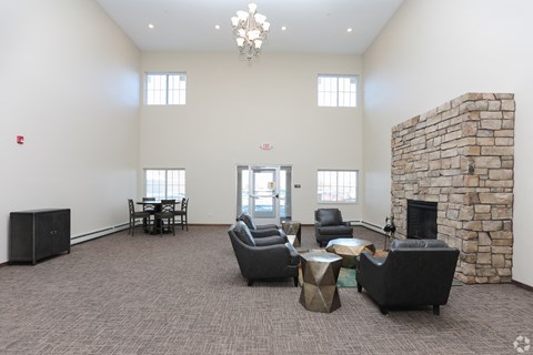 A living room with a stone fireplace and a chandelier.