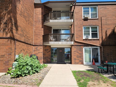 A brick building with a balcony and a small garden in front.