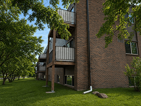 A brick building with a balcony and a tree in front.