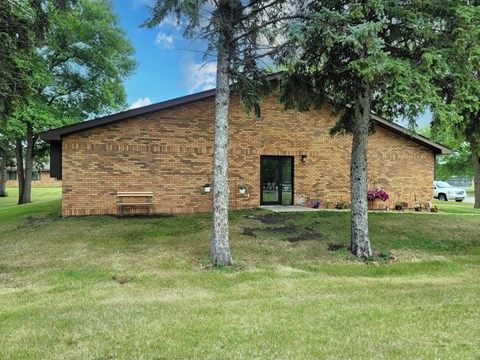 A small brick building with a tree in front of it.