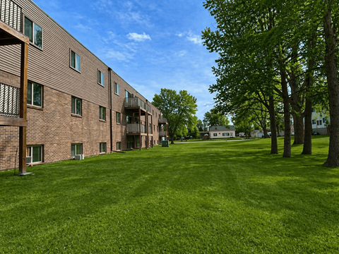 A grassy area in front of a building with trees.