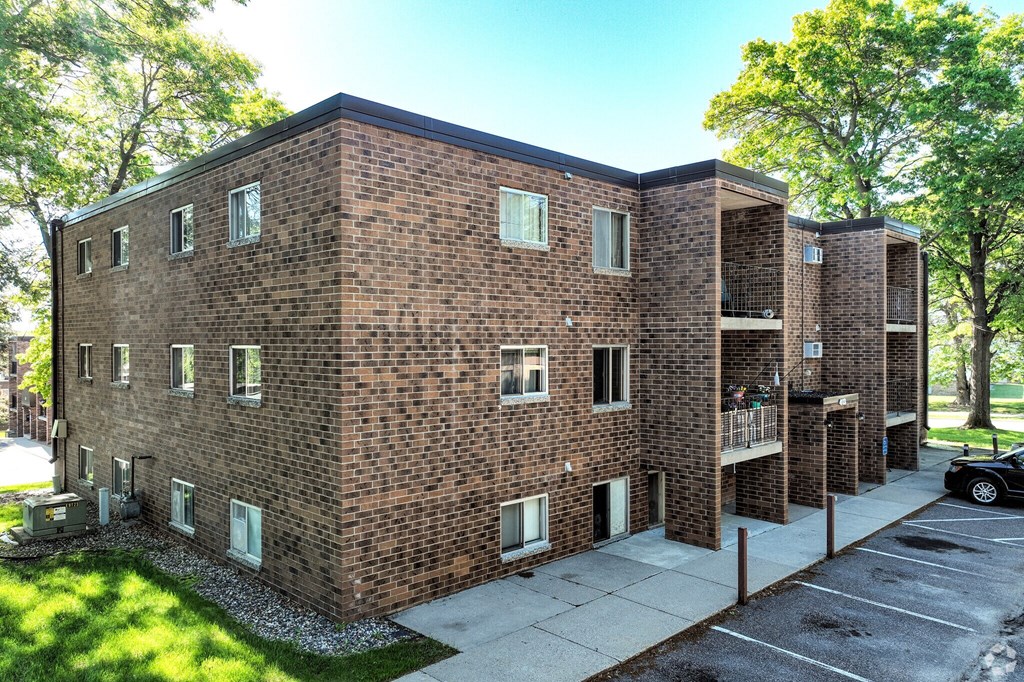 A brick building with a parking lot in front.