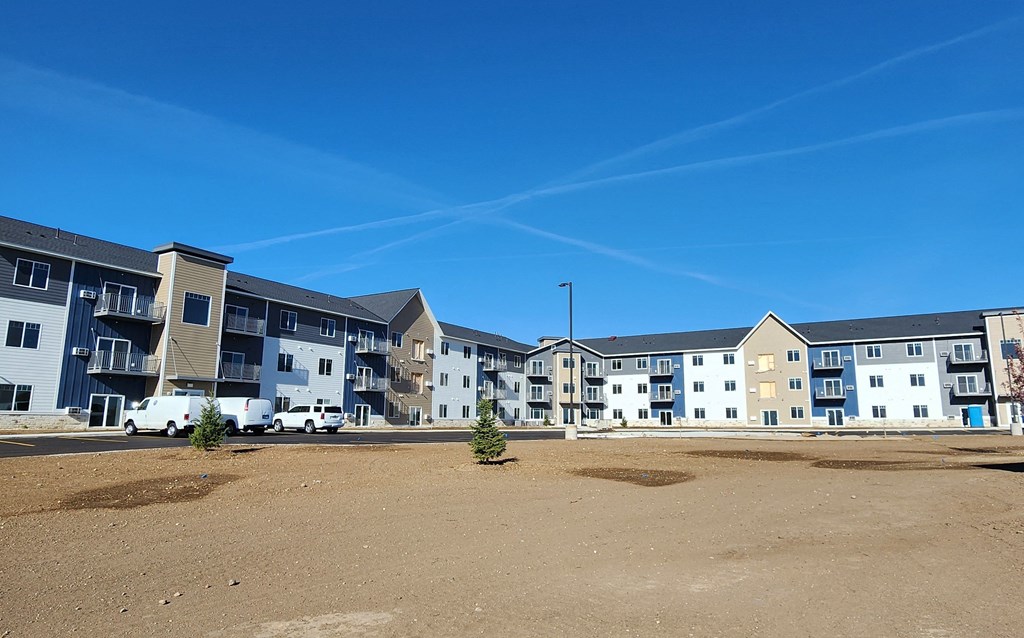 the exterior of a building with windows and a dirt field