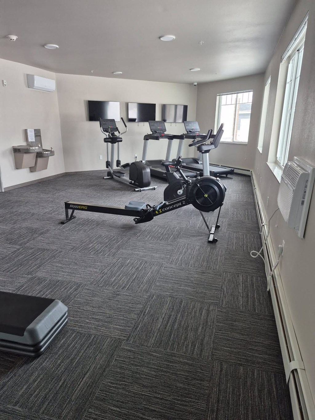 A gym with a row of treadmills and elliptical machines.