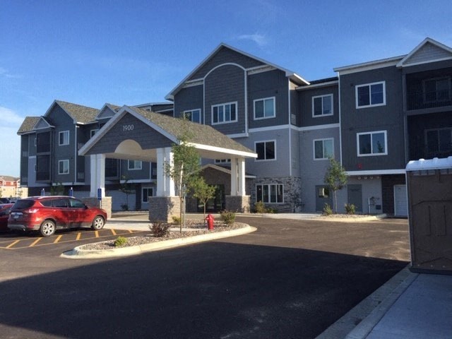 an apartment building with a red car parked in front of it