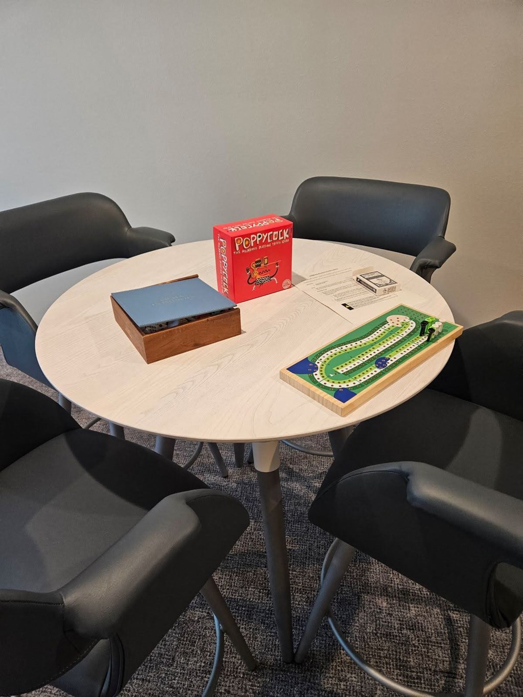 A round table with a book and a box on it surrounded by chairs.