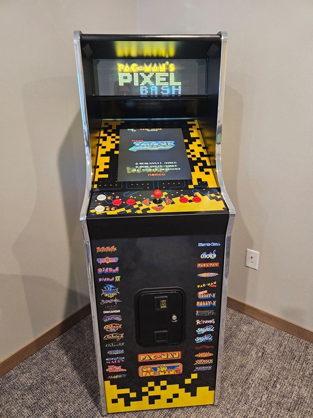A small arcade machine with a black background and yellow and black pixelated design.