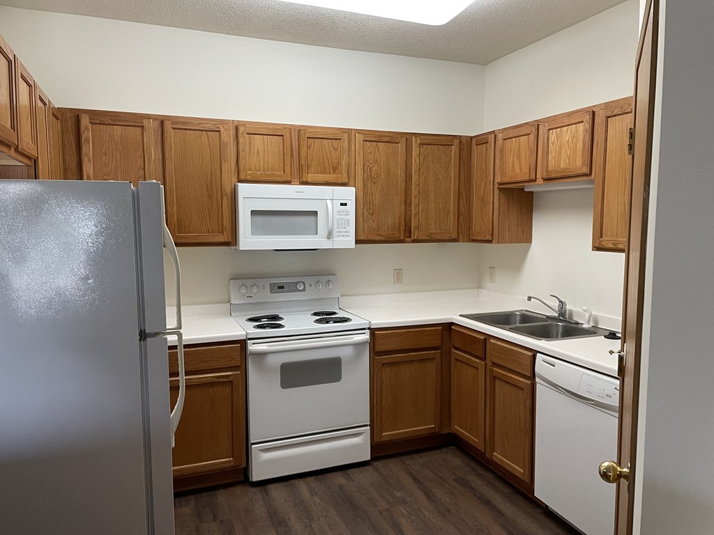 an empty kitchen with white appliances and wooden cabinets