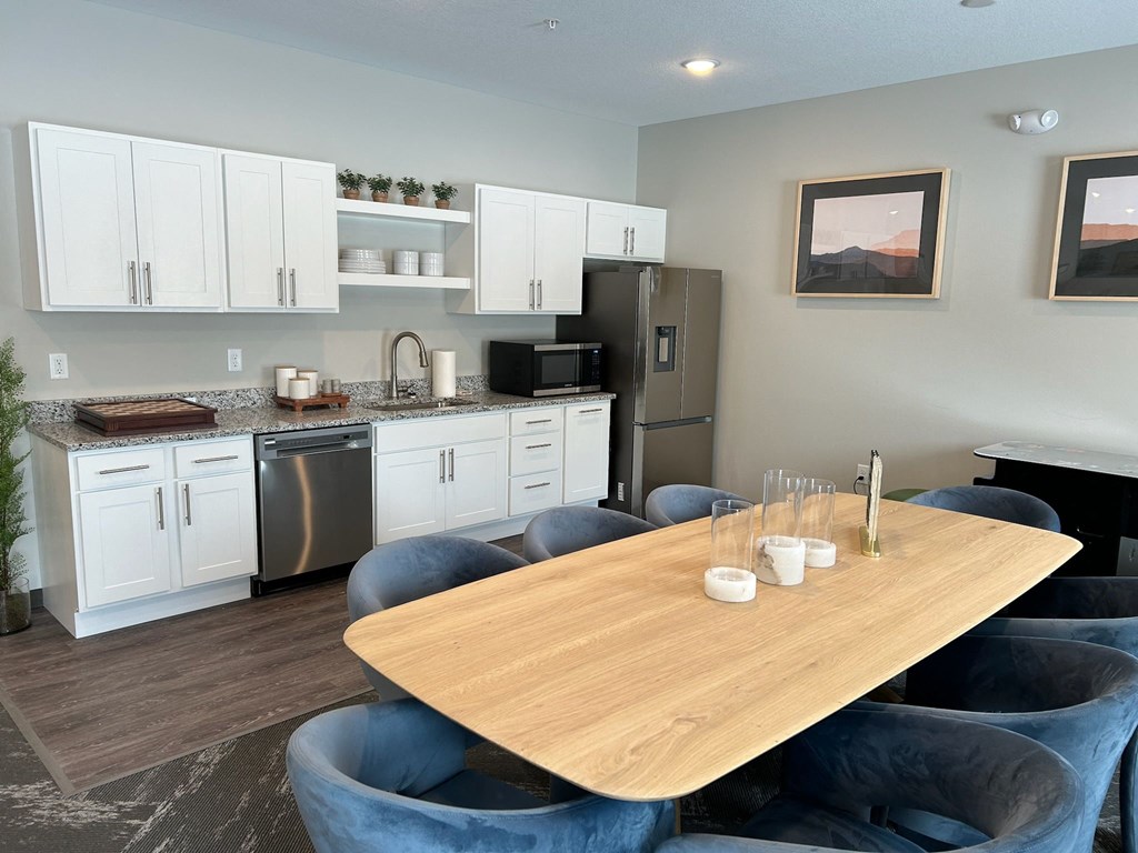 a kitchen with white cabinets and stainless steel appliances and a dining table with blue chairs