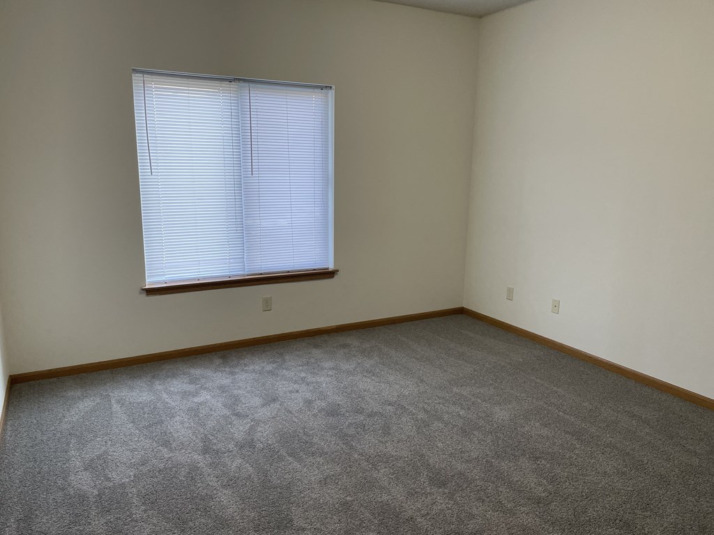 an empty room with a window and a carpet
