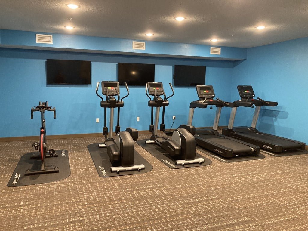 a row of exercise bikes in a gym with televisions