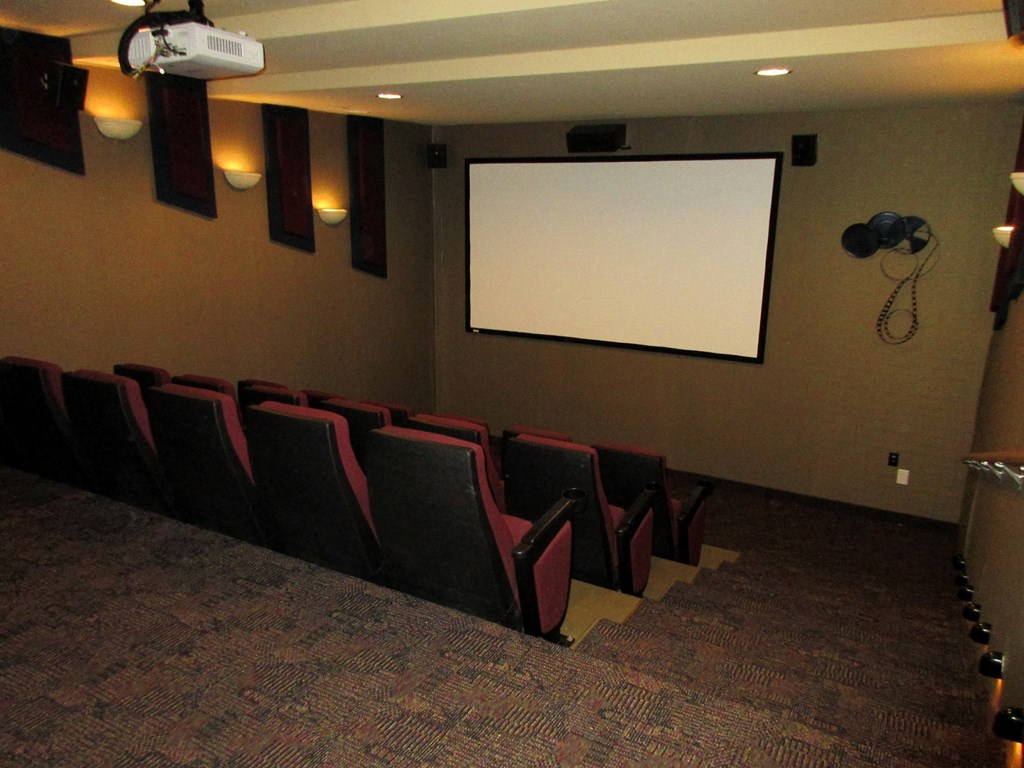 a theater room with red chairs and a projector screen