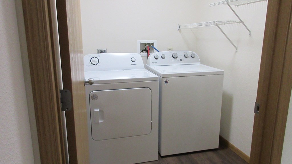A small white washing machine and dryer in a small room.