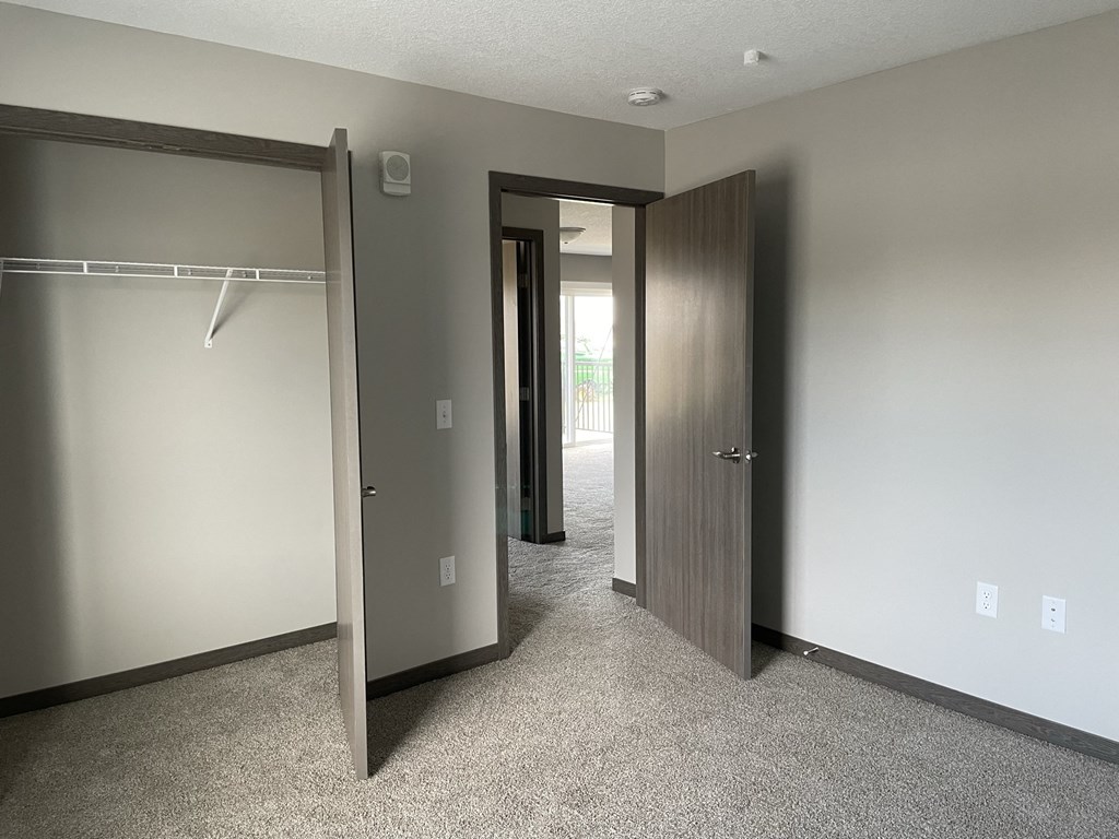 an empty bedroom with a closet and two doors