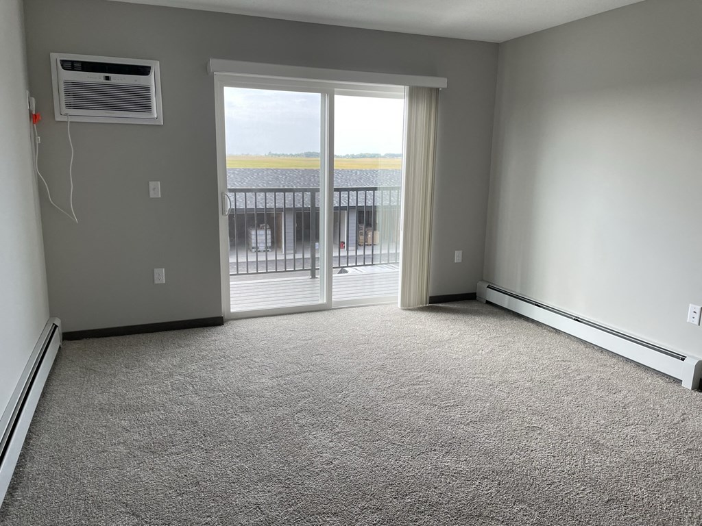 an empty living room with a door to a balcony