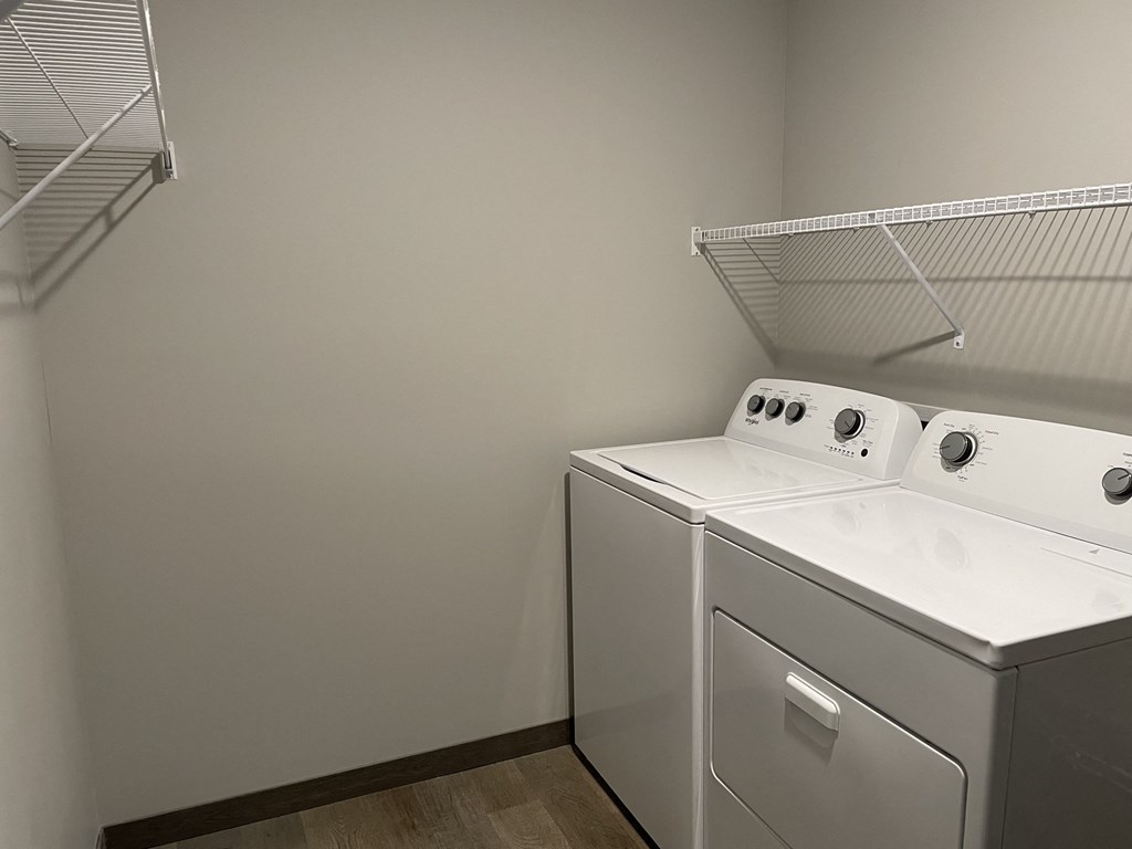 a laundry room with a washer and dryer and a shelf on the wall