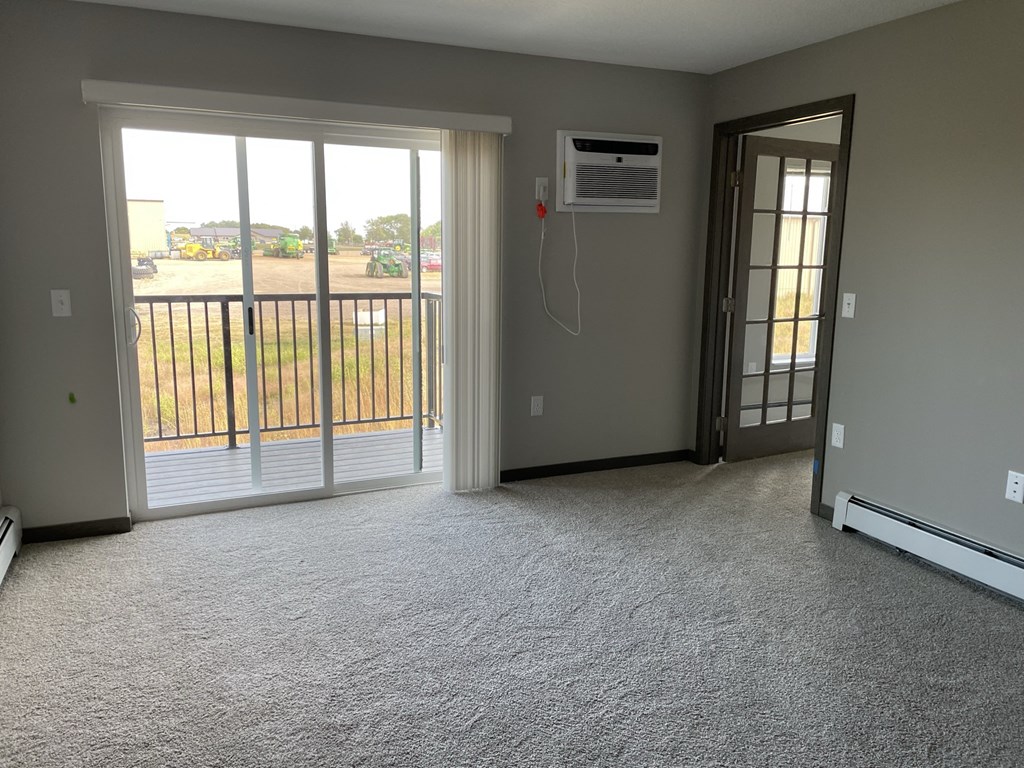 an empty living room with a sliding glass door to a balcony