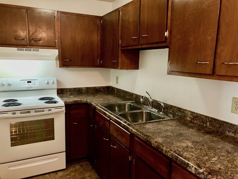 A kitchen with a white stove and brown cabinets.