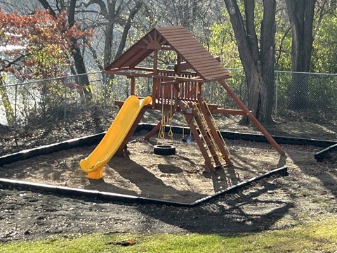 A wooden playground with a yellow slide.