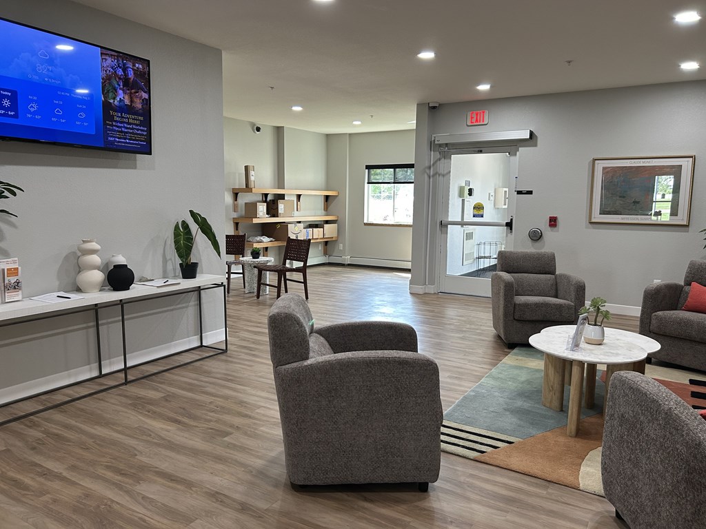 A waiting room with grey chairs and a television on the wall.