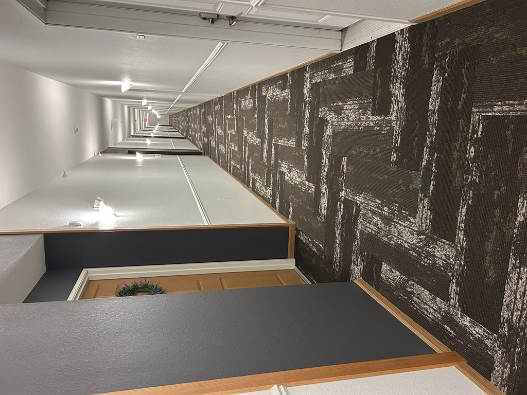 A long, narrow hallway with a black and white patterned wallpaper.