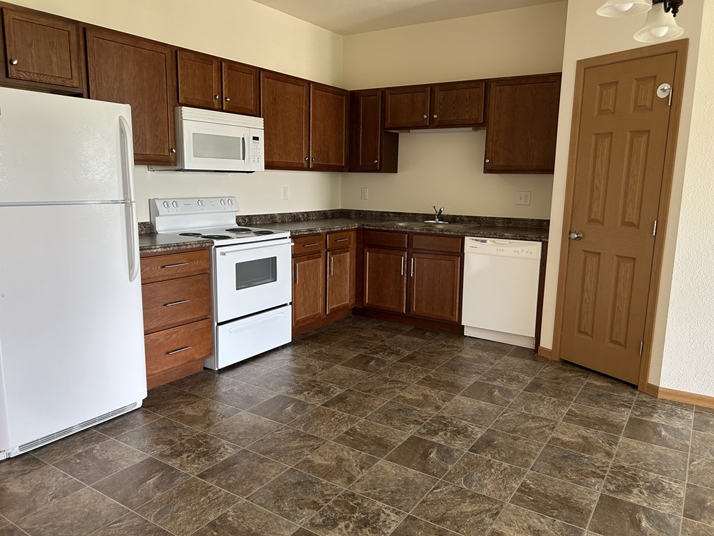 A kitchen with brown cabinets and a white refrigerator.