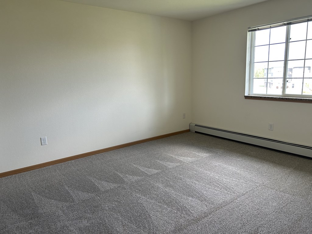 A room with a carpeted floor and a window.