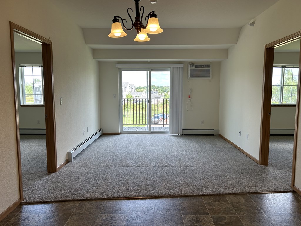 A spacious room with a carpeted floor and a chandelier hanging from the ceiling.