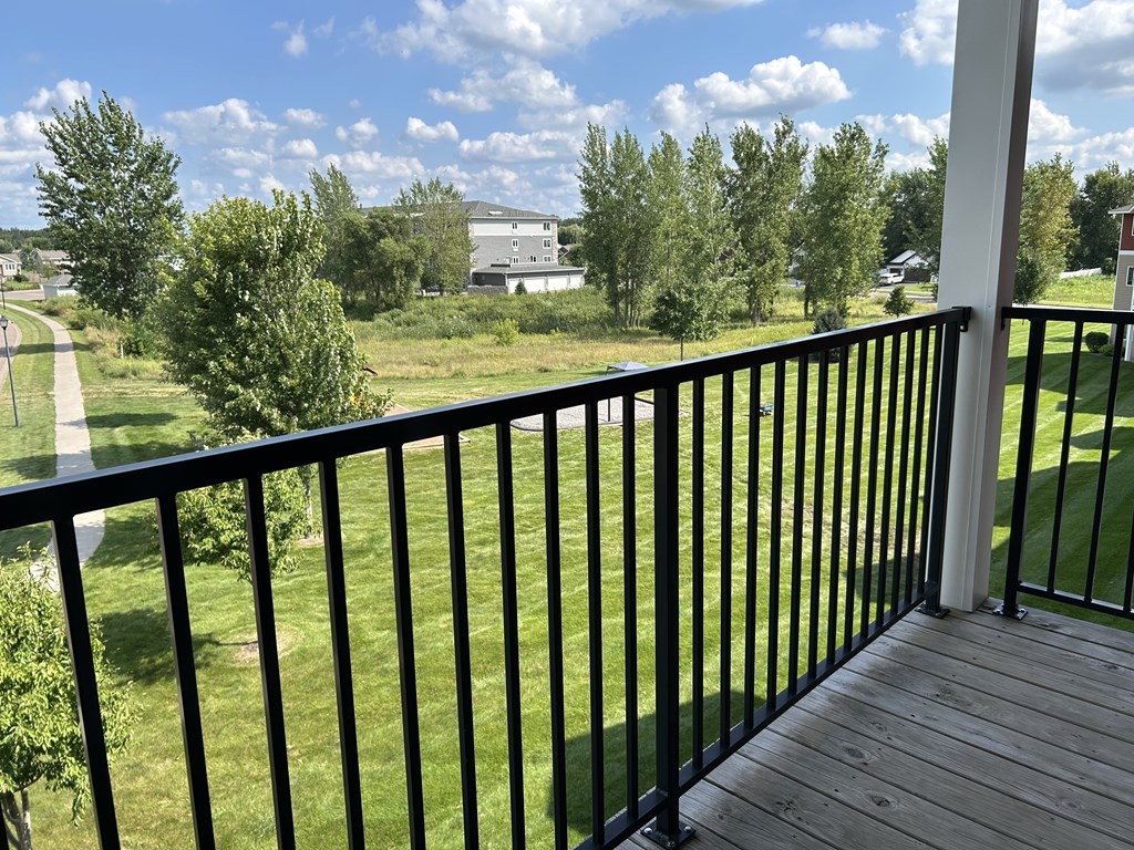 A balcony with a black railing overlooks a green lawn.