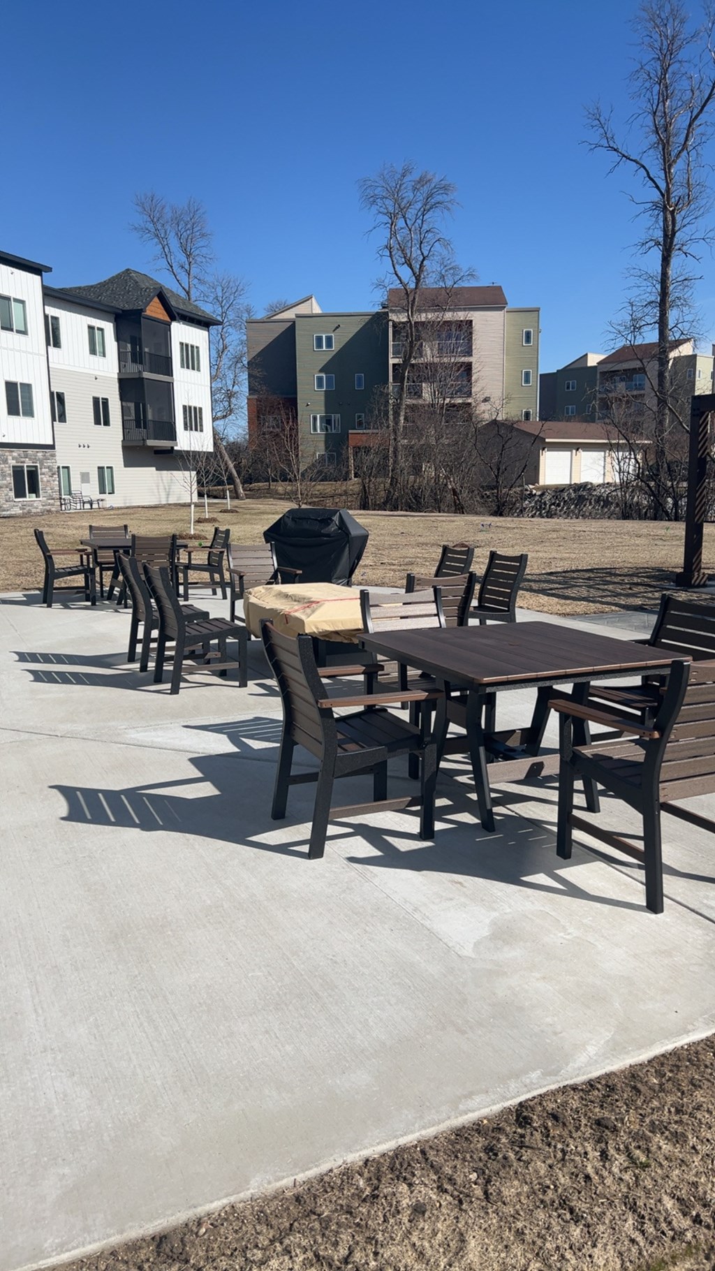 A park with a table and chairs in the foreground and apartment buildings in the background.