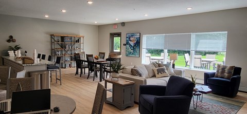 A living room with a black couch, a coffee table, and a large window with a view of the backyard.