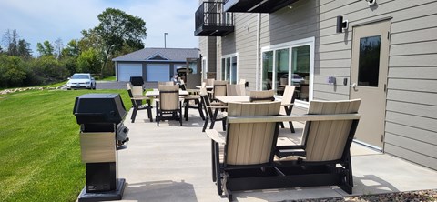 A patio with chairs and a table is in front of a house.