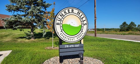 A sign for Bunker Hills Apartment Homes stands in a grassy area.