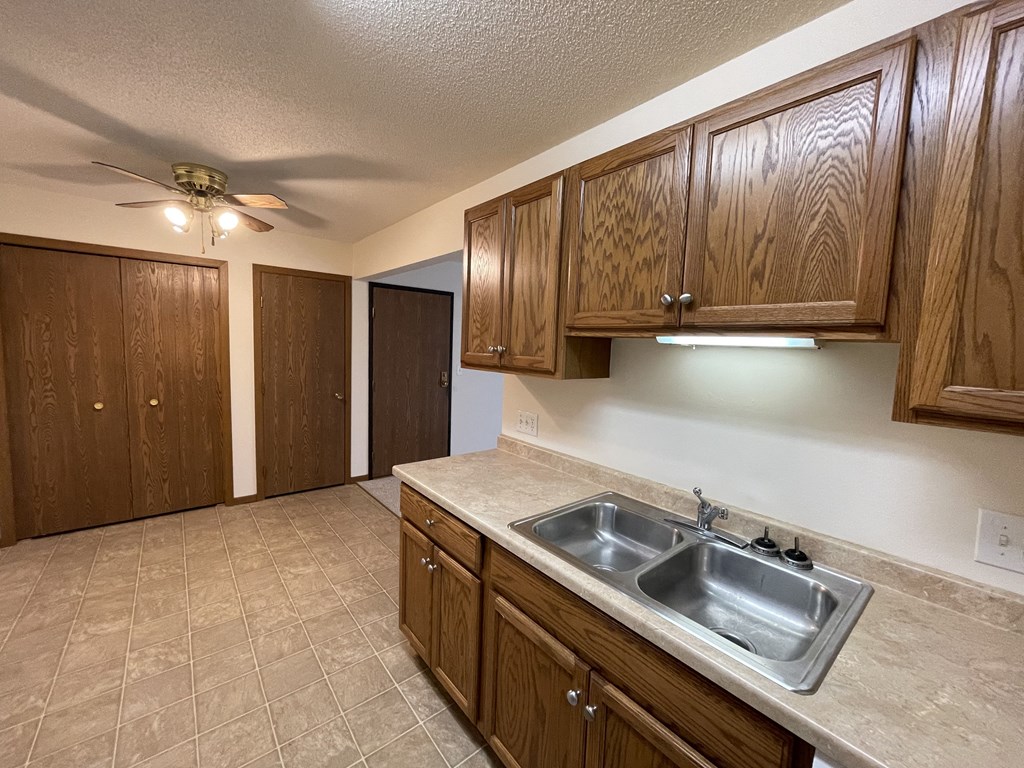 A kitchen with brown cabinets and a tile floor.