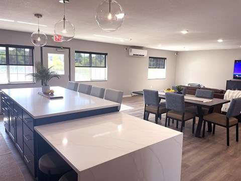 A modern kitchen with a large island and a dining area with chairs and a table.