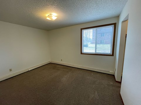 A room with a window and carpeted floor.