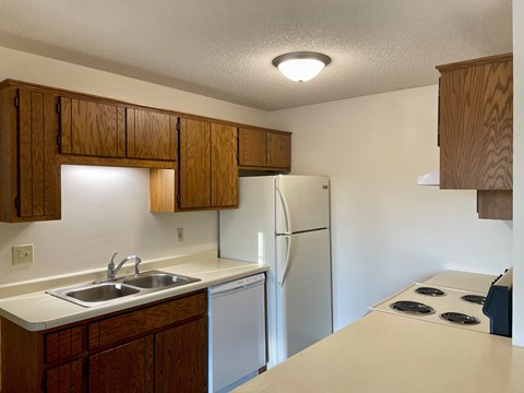A kitchen with a white counter top and a white refrigerator.