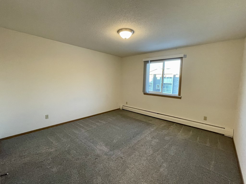 A room with a window and a grey carpet.