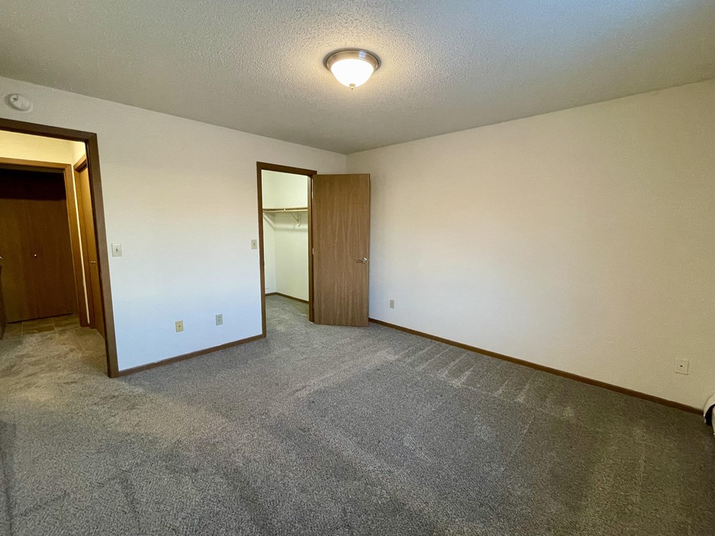 A room with a carpeted floor and two doors.