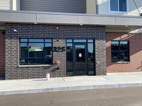 a brick building with glass doors and a sidewalk