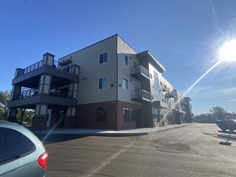 an apartment building on a street with the sun shining in the sky