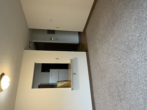 A small mirror on a wall reflects a cabinet and a shelf.