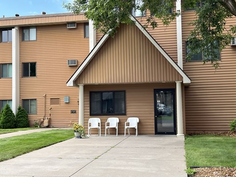 A brown house with a white chair in front.