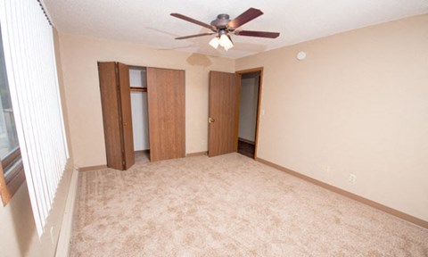 an empty living room with a ceiling fan and two doors